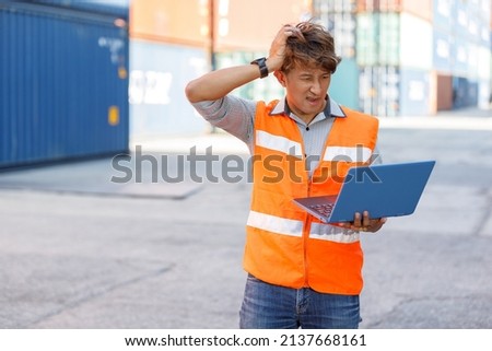 factory worker or engineer holding laptop computer and scratch his head when seeing a difficult situation at work in containers warehouse storage Royalty-Free Stock Photo #2137668161