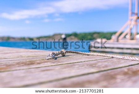 mooring's fastening for a boat floating facility on a wooden pier, a symbol of summer adventures, summer sketch in yellow and blue with a blurred seascape on the background Royalty-Free Stock Photo #2137701281