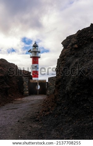 Teno lighthouse in the Canary Islands. Winter of Tenerife. Red and white lighthouse building.