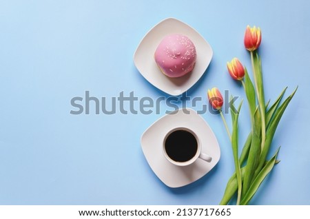 Morning with cup of hot coffee and sweet donuts on blue background. Bouquet of tulips. Top view, copy space, mockup. Flat lay. Food and drinks. Spring holidays. 