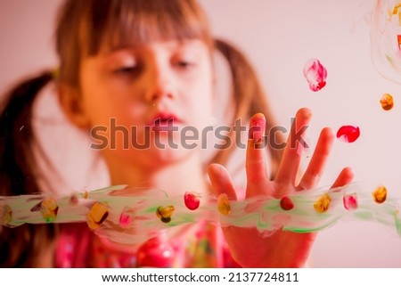 Art on the glass. Beautiful young child girl painting on glass. Happy childhood, painting lessons concept. Horizontal image. Selective focus on fingers.