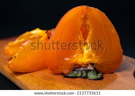 Ripe juicy persimmon on black background. Season sweet fruit Royalty-Free Stock Photo #2137733611