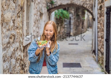 Young woman tourist eating traditional pizza in the old town of Budva. Travel to Montenegro concept