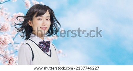 Young asian school girl blowing her hair in front of cherry blossoms. Royalty-Free Stock Photo #2137746227