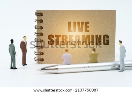 Finance concept. On a white background there are figures of businessmen, there is a pen on which the figures of businessmen sit and there is a notepad with the inscription - Live Streaming