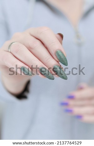 Female hand with long nails and a green manicure nail polish