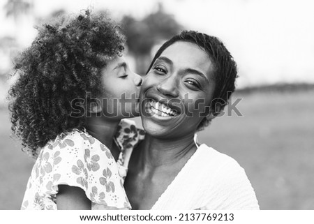Happy african mother having tender moment with her child in summer day - Focus on mom eye - Black and white editing