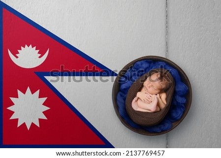 Newborn portrait on background in color of national flag. Patriotic photography concept. Nepal
