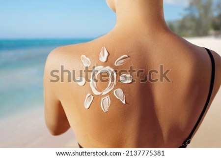 Skin care. Sun protection. Woman apply sun cream. Woman With Suntan Lotion On Beach In Form Of The Sun. Portrait Of Female With  Drawn Sun On A Shoulder. Suncream. Girl Holding Moisturizing Sunblock. Royalty-Free Stock Photo #2137775381