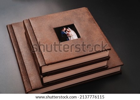 wedding photobooks in brown leather binding with photos on the cover. high-quality and expensive photo and printing products. services of a professional photographer and designer. on black background