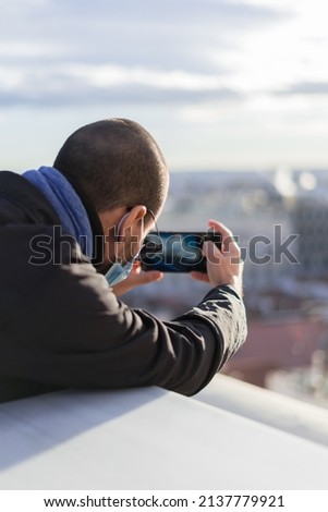 one man taking a picture of the city in a rooftop with face mask