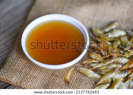 fish sauce on white bowl and small dried fish on sack, fish sauce obtained from fermentation fish or small aquatic animal, fermented foods Royalty-Free Stock Photo #2137782681