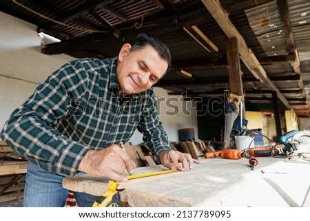 Mexican carpenter working in his workshop-Smiling mature man working in carpentry workshop-Happy carpenter working