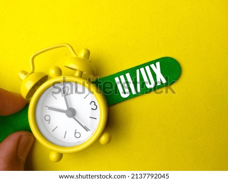 Hand holding colored icr cream stick and clock with text UI UX on yellow background.