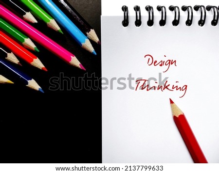 Color pencils and notebook with handwritten text DESIGN THINKING, means process for creative problem solving which focus on people they creating for, human-centered core innovation