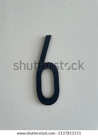 3D number 6 symbol in black on a beige wall