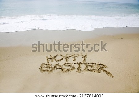 Hoppy Easter. The words HOPPY EASTER written in the sand by the ocean. Easter Sunday is a day to celebrate at the beach or anywhere you like. Hoppy Easter to all.  Royalty-Free Stock Photo #2137814093