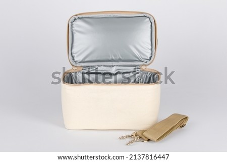 Closeup studio shot opening showing inside compartments of multifunction multipurpose hot and cold temperature control baby toddler mommy bag with long adjustable strap on white background