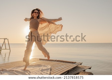 Bottom view of happy caucasian young girl admiring sunrise or sunset on tropical beach. Brown-haired woman in sunglasses is having fun. Nice vacation by the sea. Royalty-Free Stock Photo #2137818575