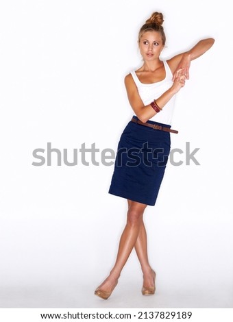 Sleek and stylish. A fashionable young woman leaning on an imaginary surface over a white background.