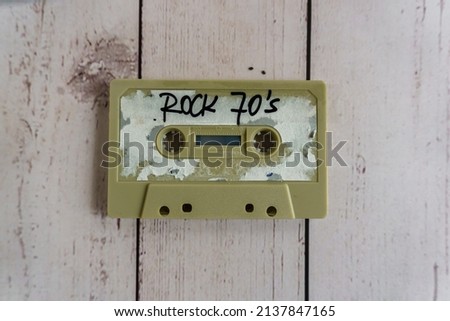 Vintage cassette tape isolated on wooden background with sign reading rock 70s
