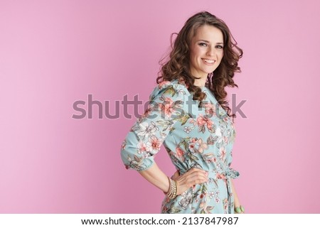Portrait of happy modern woman in floral dress with bracelets isolated on pink background.
