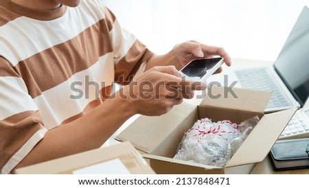 Online shopping concept the merchant using his mobile phone to take a picture of his product in the box.