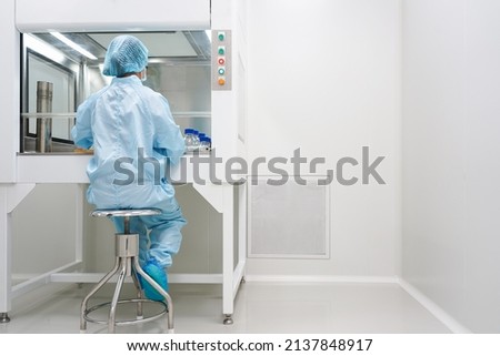 Unidentified microbiologist is testing the sample under the laminar air flow cabinet in the clean room of quality control laboratory in pharmaceutical industry. Royalty-Free Stock Photo #2137848917