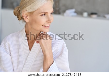Headshot of happy smiling gorgeous middle aged woman in bathrobe at spa hotel looking away. Advertising of bodycare spa procedures antiage recreation skin care products concept. Royalty-Free Stock Photo #2137849413