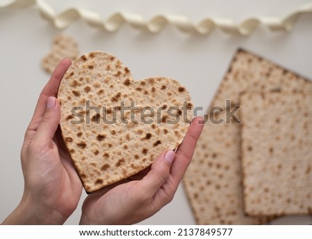 Woman's hand holds Matzah shape of heart. Traditional of Jewish Holiday on Passover. Home symbol of lovely family. top view, layout. love and care. Gift for lovers. Feeling in love and blissful life Royalty-Free Stock Photo #2137849577