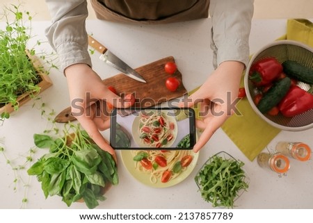 Woman making photo of tasty pasta on light background