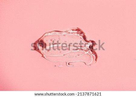 Cream gel drops red transparent cosmetic sample texture with bubbles on pink background. texture hyaluron