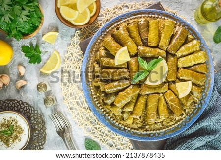 Arabic Cuisine; Traditional delicious stuffed vine leaves. Served with yogurt salad and fresh lemon. Top view with close up. Royalty-Free Stock Photo #2137878435