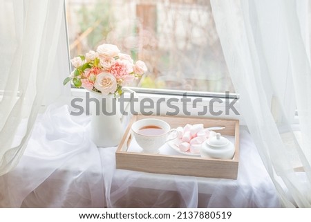a spring still life, a bouquet of roses in a vase, a cup of tea and an old book are lying on the window. spring greeting card with spring flowers