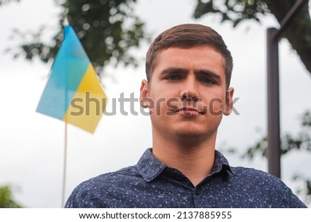 Ukrainian man. Young man holding ukrainian flag. No war. Support for Ukraine. Patriotic Spirit rising hand of Ukraine flag. freedom ukraine. Nature background. People, person. Activist. Face.