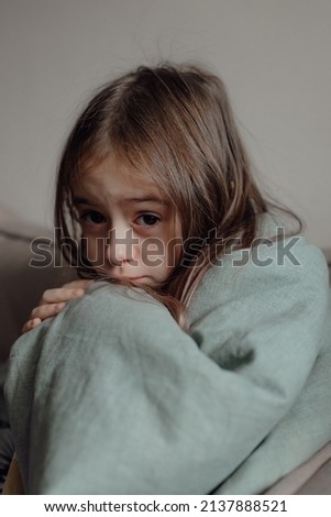 Stop war. Pray for Ukraine. we stand with Ukraine. Ukrainian frightened child under a blanket. The girl is afraid of the sounds of air raids and explosions. Poor child feeling sorrow and sadness.