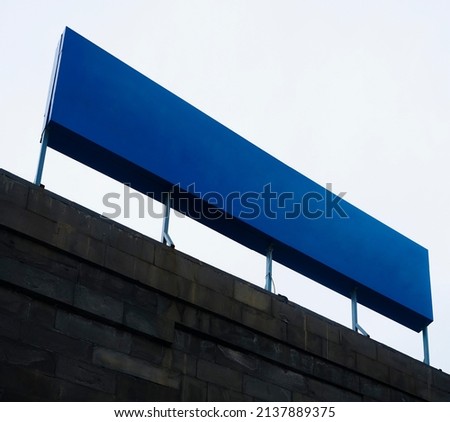 Blank blue square sign on glas wall mockup, sky background. Empty quadratic exterior box for clinic or club mock up. Clear office facade with bank or store lightbox mokcup template