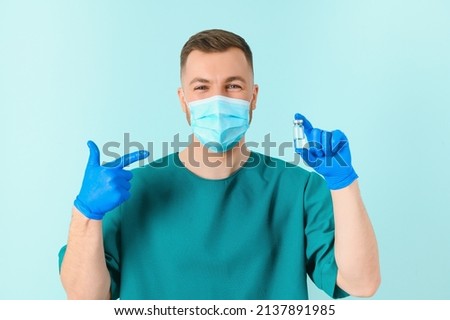 Vaccination against coronavirus. Testing COVID-19 vaccines. A male doctor in a medical mask fills a syringe the with a COVID-19 vaccine on a blue background. Doctor's hands hold a syringe close-up.