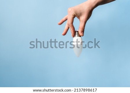 energy saving light bulb in hand on a blue background,