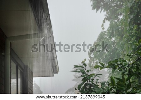 Roof gutter overflow in the heavy rain. Rain water cascading over the gutter.  Royalty-Free Stock Photo #2137899045