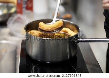 churros are fried in boiling oil in a frying pan. Wet the boiling oil with a sponge in the pan. Close-up of churros in boiling oil with lots of bubbles in a pan. Selective focus. Churros being fried Royalty-Free Stock Photo #2137901845