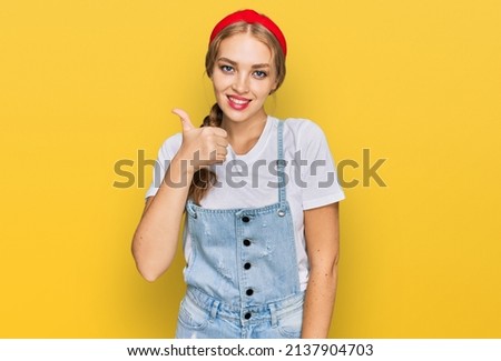 Young caucasian girl wearing casual clothes doing happy thumbs up gesture with hand. approving expression looking at the camera showing success. 