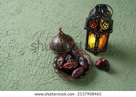 An illuminated Moroccan decorative lamp and dates in an old, antique plate. Ramadan background concept