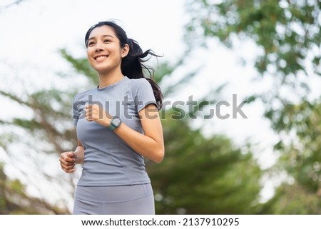 Happy slim woman wearing sportswear jogging in the city at sunrise. Young beautiful asian female in sports bra running outdoor. Workout exercise in the morning. Healthy and active lifestyle concept. Royalty-Free Stock Photo #2137910295