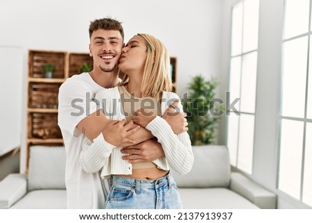 Young caucasian couple smiling happy hugging and kissing at home.