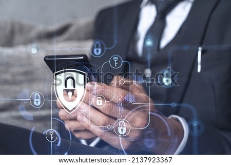 A programmer is browsing the Internet in smart phone to protect a cyber security from hacker attacks and save clients confidential data. Padlock Hologram icons over the typing hands. Formal wear.
