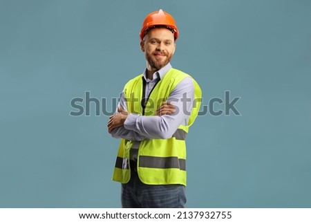 Young male site engineer with a safety vest and hardhat isolated on blue background Royalty-Free Stock Photo #2137932755