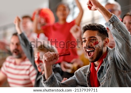 Excited football fans supproting Austrian national team in live soccer match at stadium. Royalty-Free Stock Photo #2137939711