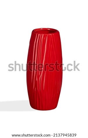 Subject shot of a red ceramic glossy vase with an imitation of a tree bark. The designer glazed vase with a textured surface is isolated on the white background.