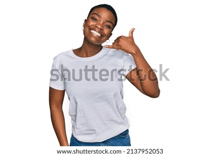 Young african american woman wearing casual white t shirt smiling doing phone gesture with hand and fingers like talking on the telephone. communicating concepts. 